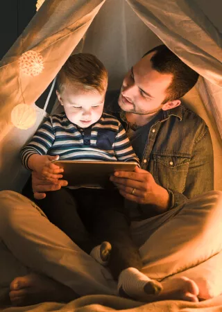 Dad reading to toddler son from tablet